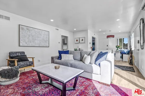 a living room with furniture a rug and kitchen view