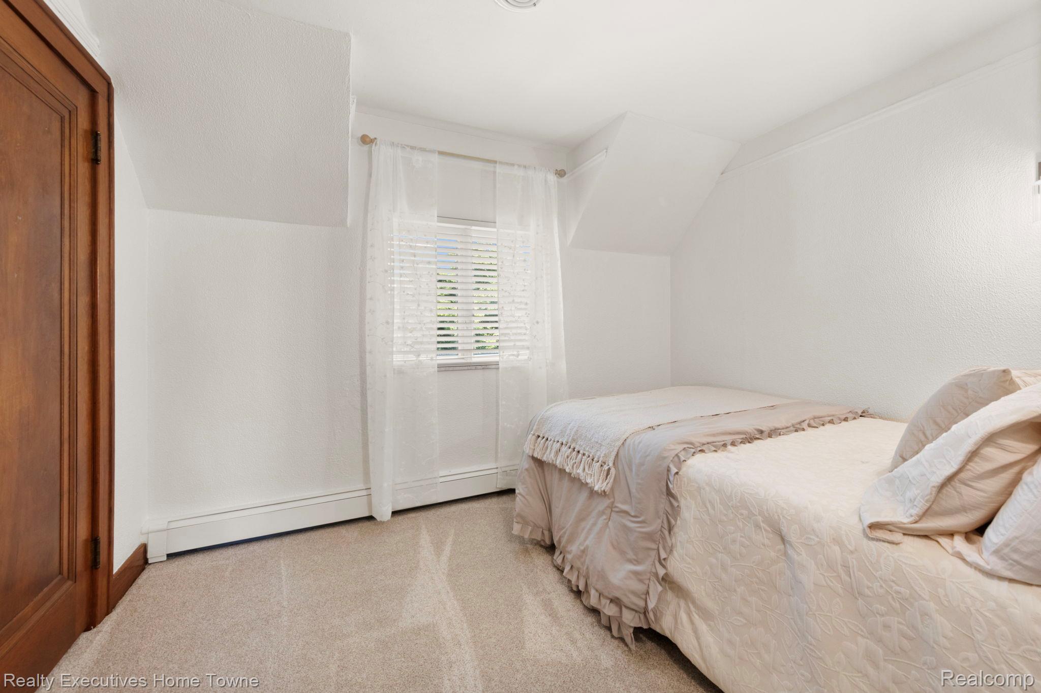 8308 Lakeshore Road Fort Gratiot, MI 48059 - Photo 53 of 79 Carpeted room featuring a single window with blinds, wood-finish door, white baseboard heating, and an angled ceiling line