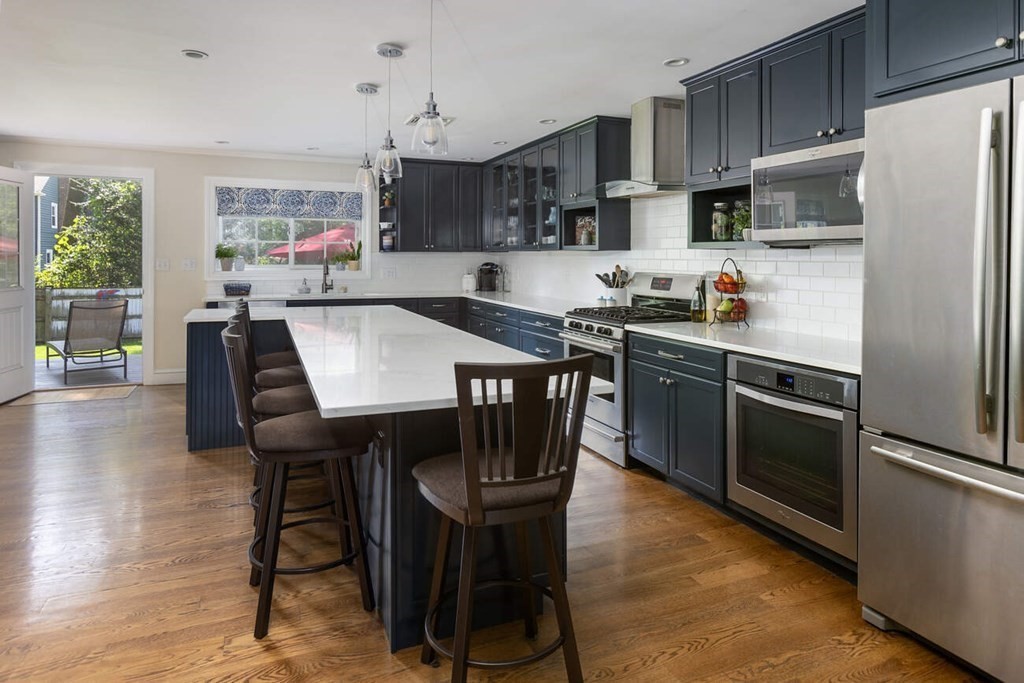 25 Plowgate Road Brookline, MA 02467 - Photo 3 of 19 a kitchen with stainless steel appliances granite countertop a dining table chairs refrigerator and sink