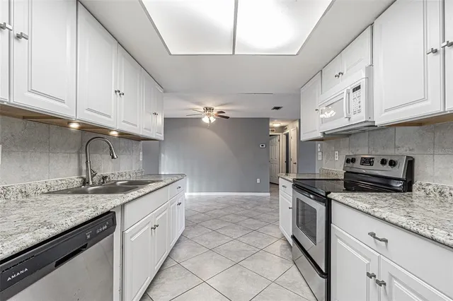 a kitchen with granite countertop a sink stainless steel appliances and white cabinets