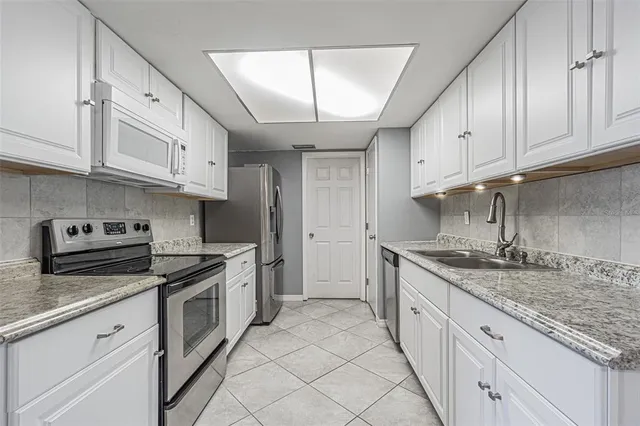 a kitchen with granite countertop a sink stainless steel appliances and cabinets