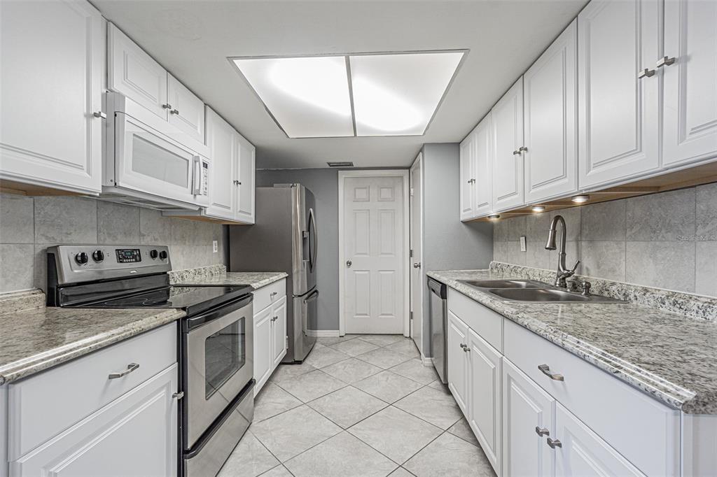 1529 Larkin Road Spring Hill, FL 34608 - Photo 3 of 37 a kitchen with granite countertop a sink stainless steel appliances and cabinets