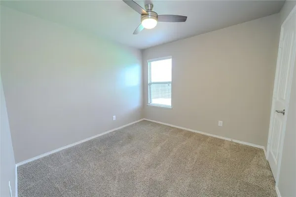an empty room with a window and ceiling fan