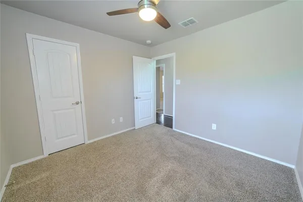 a view of an empty room and chandelier fan