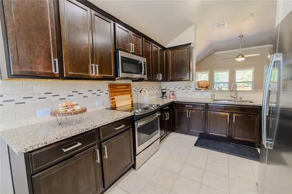 a kitchen with stainless steel appliances granite countertop a stove a sink and a microwave
