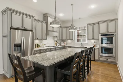 a kitchen with granite countertop a table chairs stainless steel appliances and cabinets