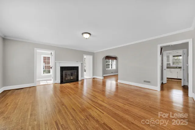 a view of an empty room with window and wooden floor