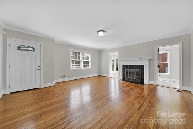an empty room with wooden floor fireplace and windows