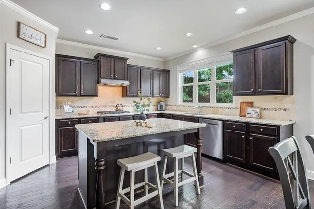 a kitchen with stainless steel appliances kitchen island granite countertop a stove refrigerator and microwave