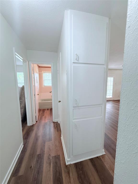 160 Bob White Road Denison, TX 75020 - Photo 14 of 29 Hallway featuring wood-finish flooring, white walls, and built-in white cabinetry providing vertical storage