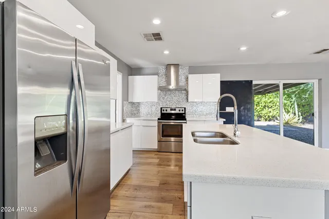 a kitchen with stainless steel appliances kitchen island granite countertop a refrigerator a sink a stove and oven