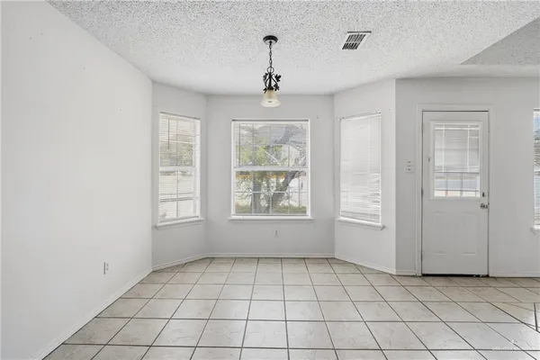 an empty room with windows and chandelier fan