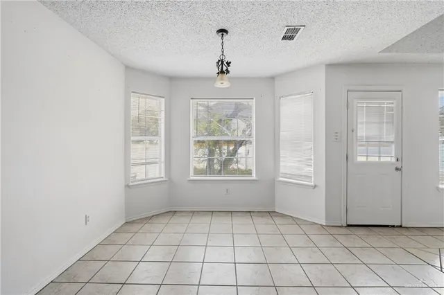 an empty room with windows and chandelier fan