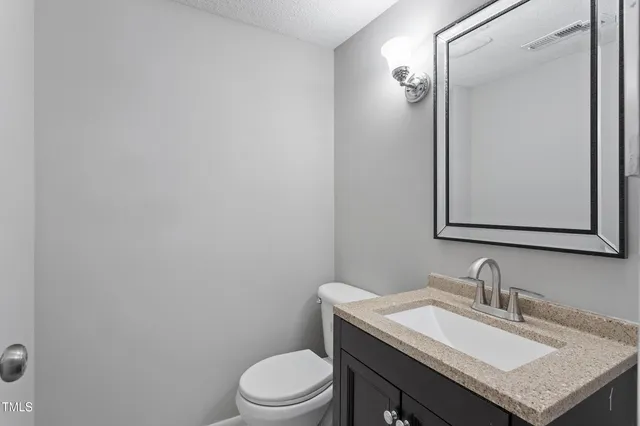 a bathroom with a granite countertop sink vanity mirror and toilet