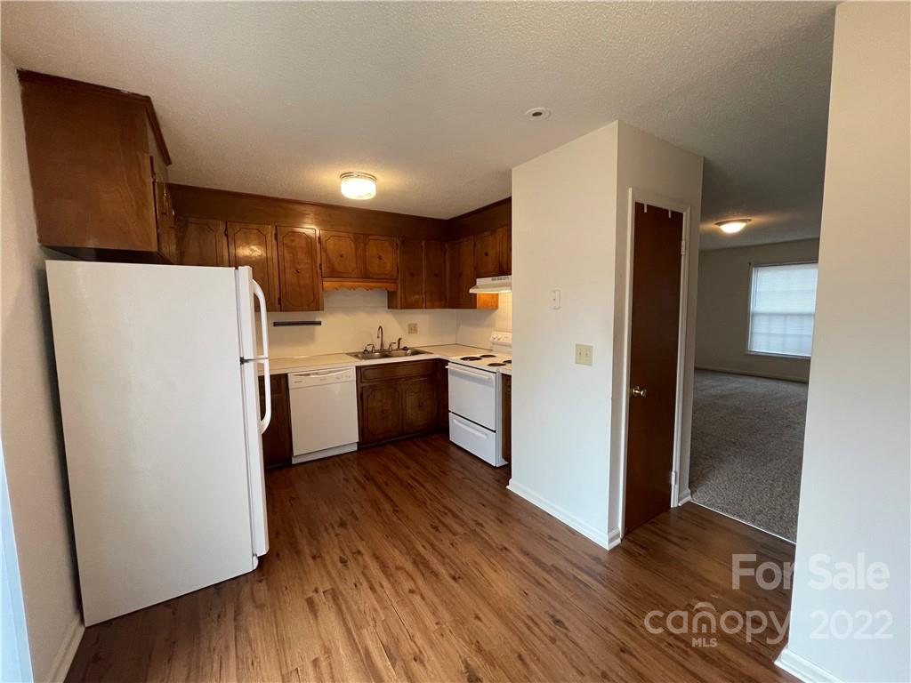 4887 County Home Road, Unit A1J2 Conover, NC 28613 - Photo 17 of 28 a kitchen with a refrigerator a stove top oven a wooden floor and a window