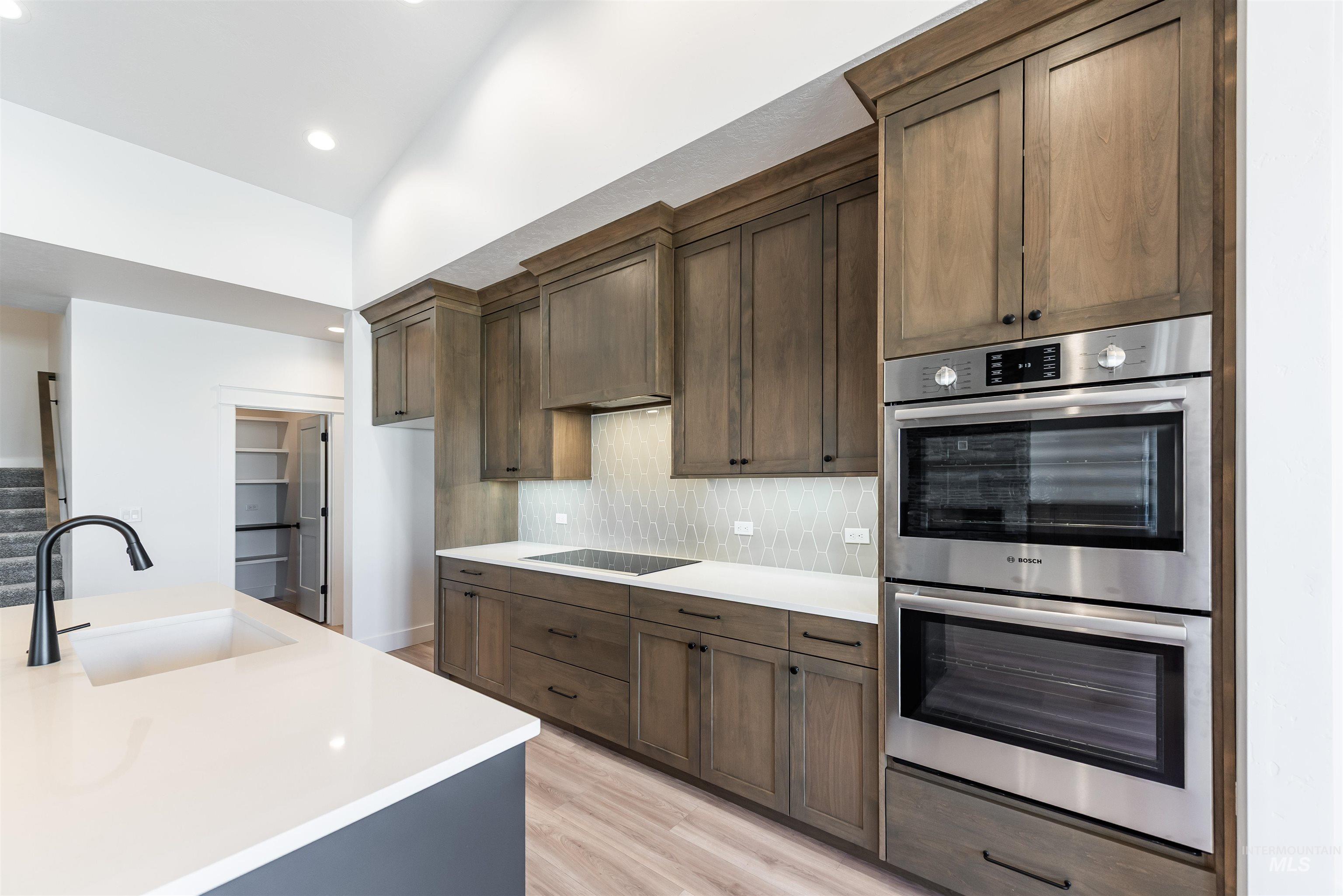 400 South Diesel Way Boise, ID 83716 - Photo 12 of 44 Kitchen with stainless steel double oven, light wood-style floors, decorative backsplash, light stone counters, and lofted ceiling