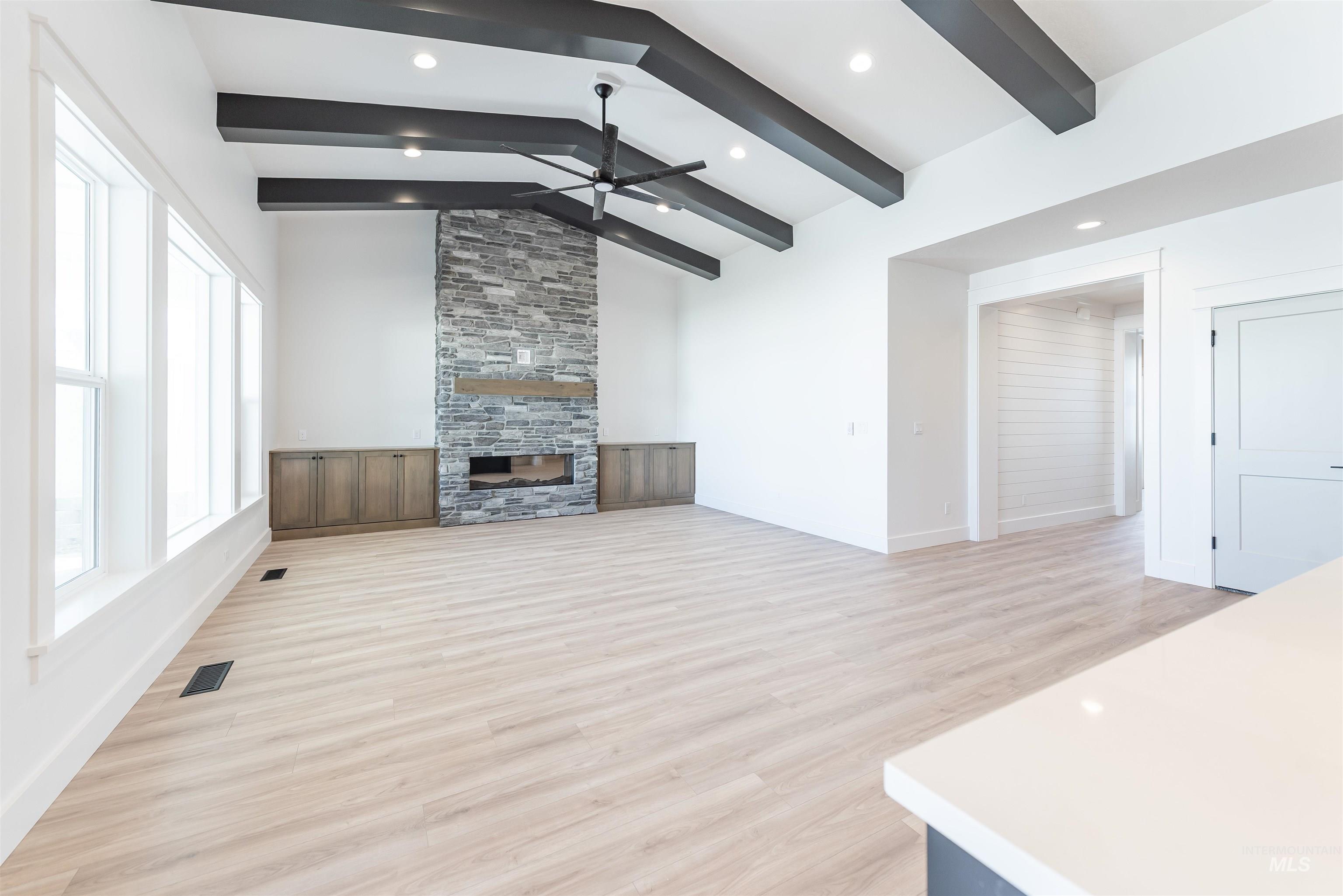 400 South Diesel Way Boise, ID 83716 - Photo 15 of 44 Unfurnished living room featuring light wood finished floors, lofted ceiling with beams, recessed lighting, a stone fireplace, and a ceiling fan