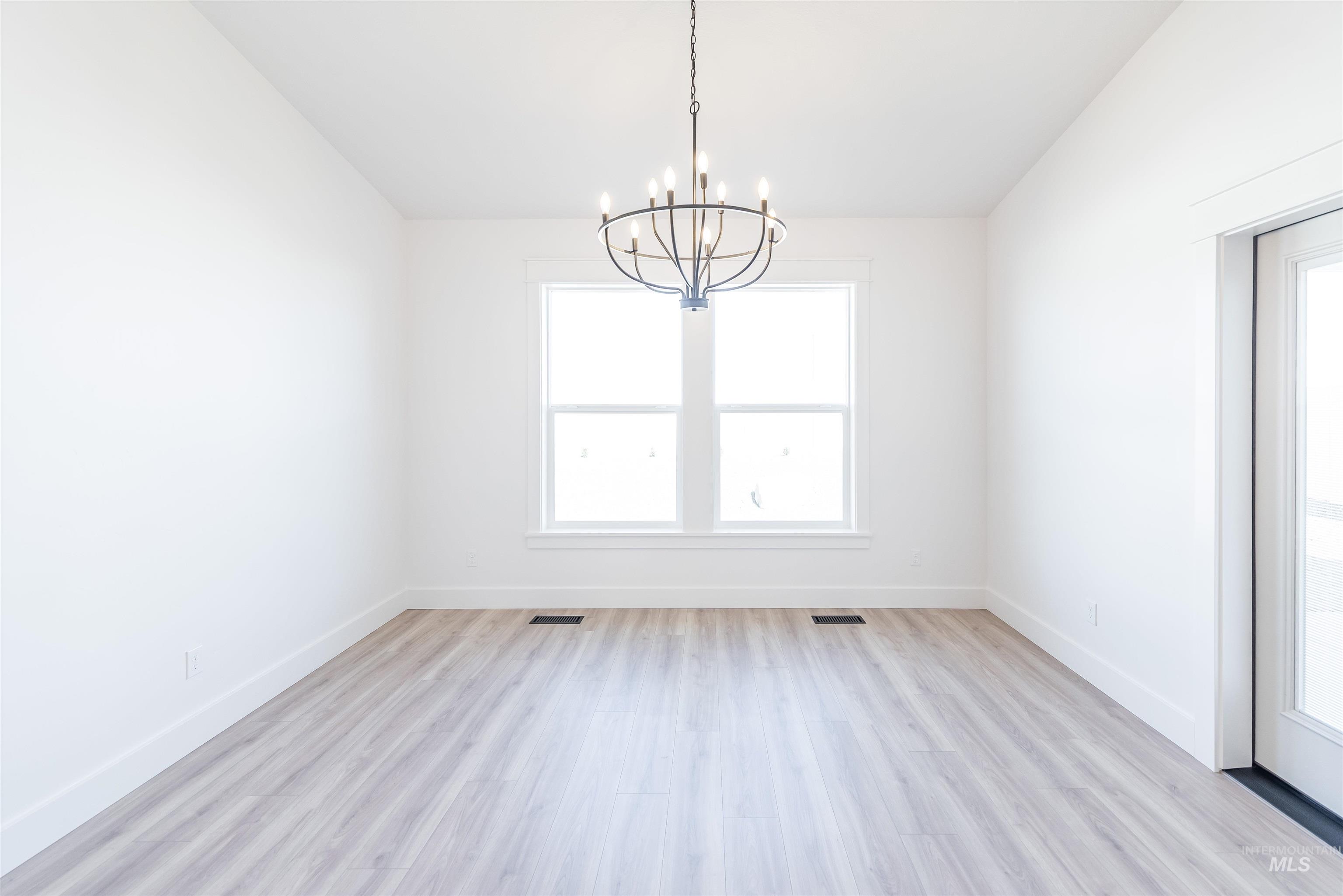 400 South Diesel Way Boise, ID 83716 - Photo 8 of 44 Unfurnished dining area with a chandelier, vaulted ceiling, light wood finished floors, and healthy amount of natural light