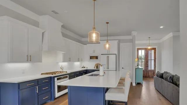 a kitchen with granite countertop a stove a sink a refrigerator a living room dining table and chairs