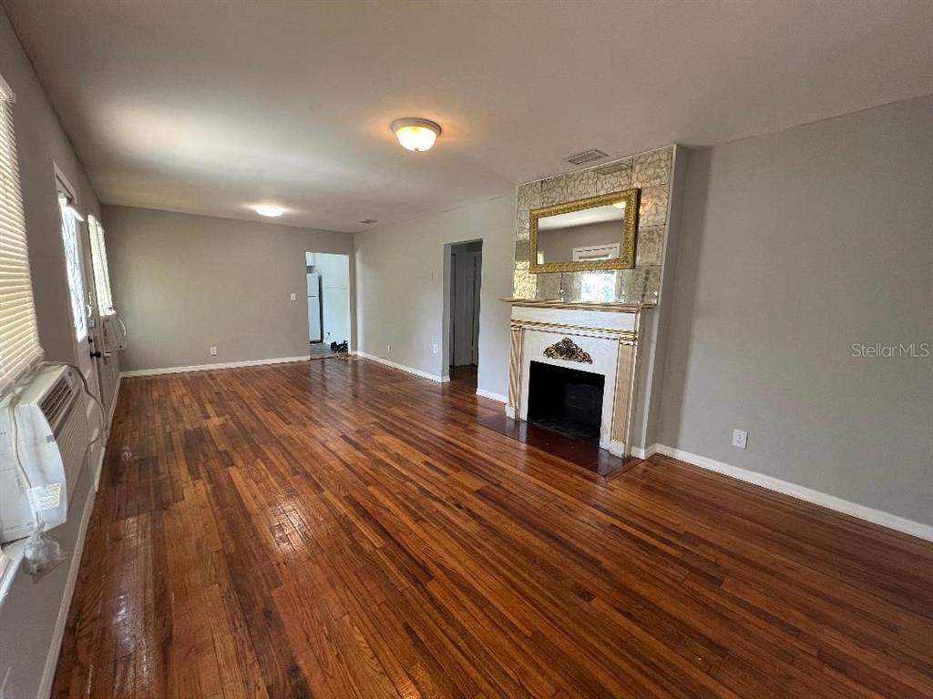 Undisclosed Address Tampa, FL 33609 - Photo 2 of 7 an empty room with wooden floor and fireplace