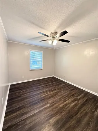 a view of a room with wooden floor a ceiling fan and windows