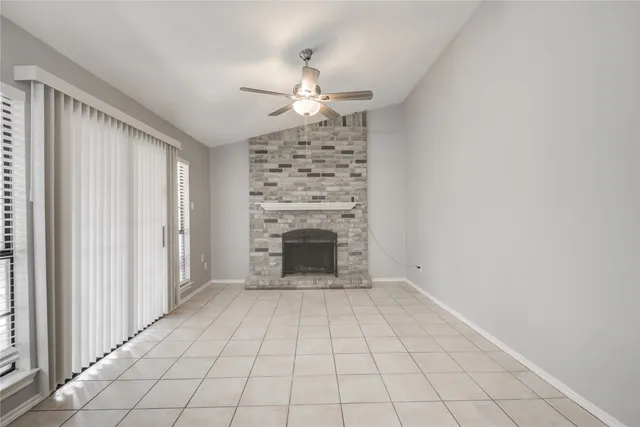 an empty room with windows and fireplace