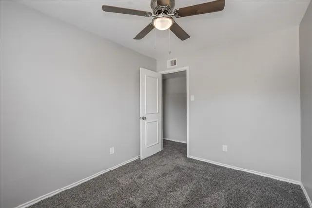 a view of an empty room and chandelier fan