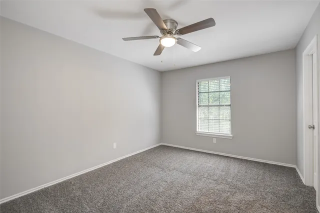 an empty room with windows and ceiling fan