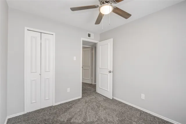 an empty room with closet and a chandelier fan