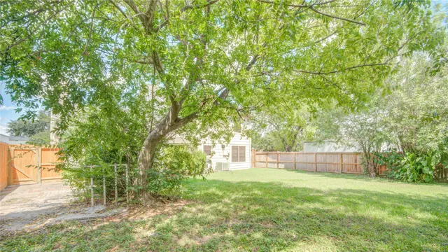 a backyard of a house with lots of plants and large trees