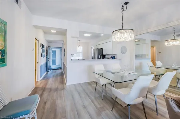 a view of a dining room and livingroom with furniture wooden floor a chandelier