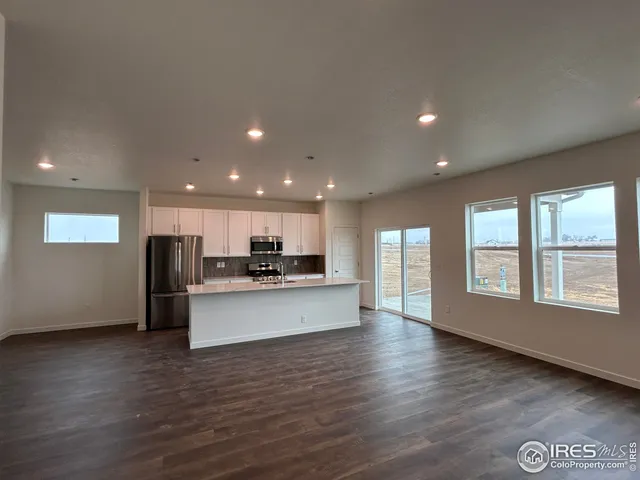 a view of kitchen with kitchen island stainless steel appliances wooden floor and window
