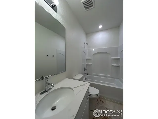 a bathroom with a granite countertop sink a toilet and shower