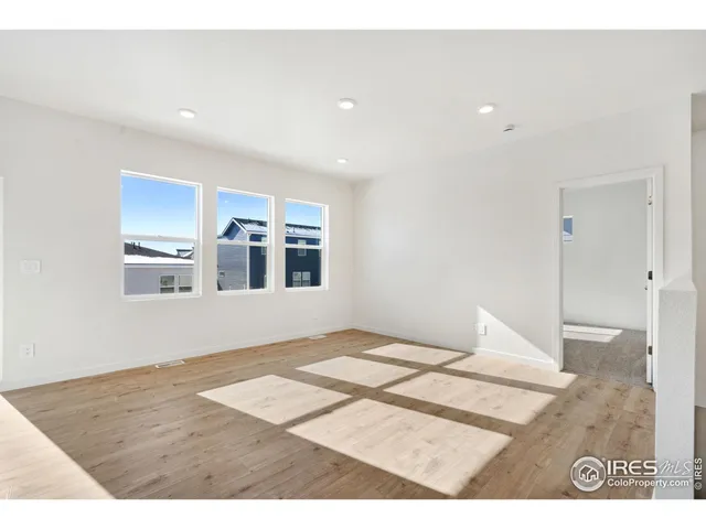 a view of an empty room with window and wooden floor