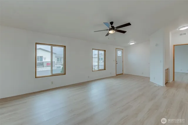 a view of an empty room with a window and wooden floor
