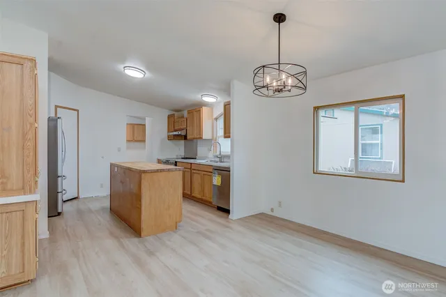 a open kitchen with stainless steel appliances granite countertop a refrigerator a stove oven a sink dishwasher and white cabinets with wooden floor