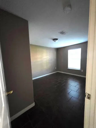 an empty room with wooden floor and windows with curtains