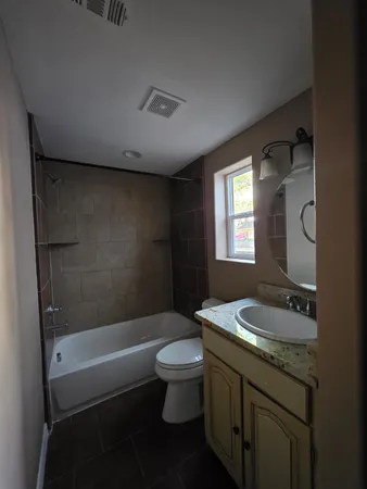 a bathroom with a granite countertop sink a toilet a mirror and bathtub