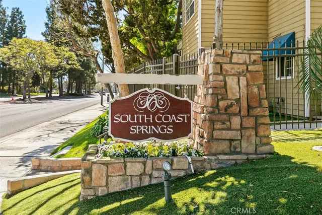a view of tall building with large trees and cars parked