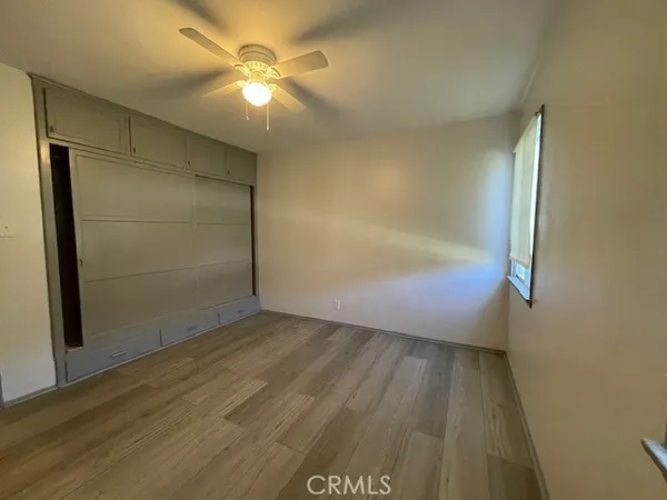 an empty room with wooden floor and a ceiling fan