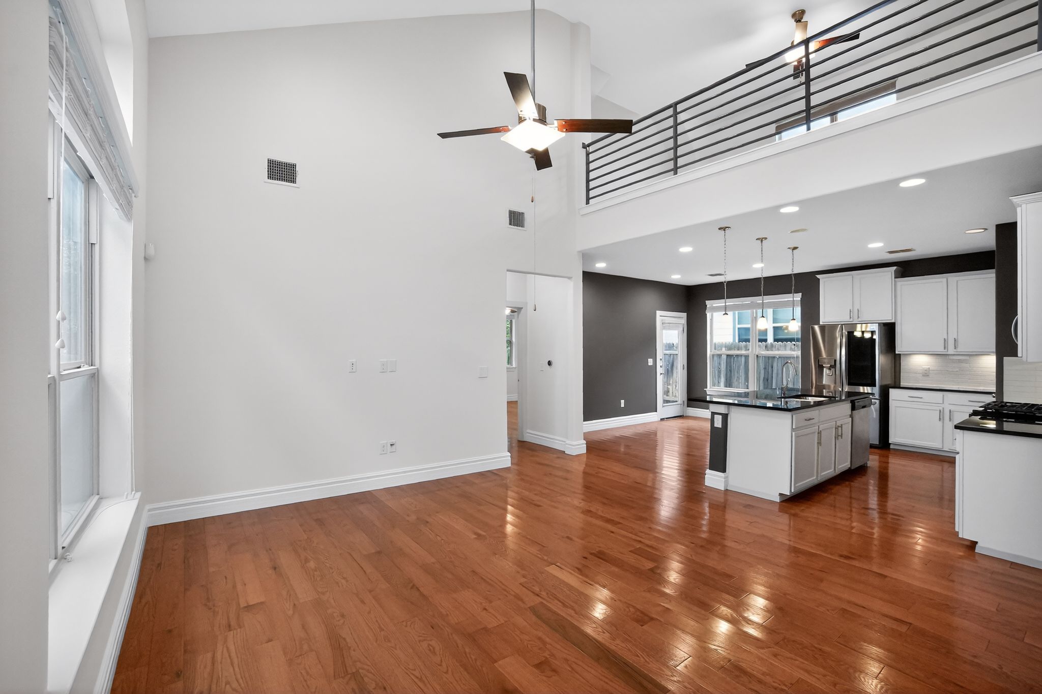 9717 Briny Shell Way Austin, TX 78748 - Photo 15 of 16 Kitchen featuring white cabinets, a high ceiling, open floor plan, decorative light fixtures, and dark wood-style flooring