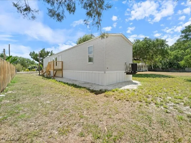 a view of backyard with large tree and wooden fence