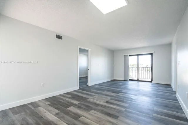 a view of an empty room with window and wooden floor