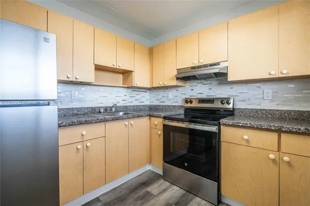 a kitchen with stainless steel appliances granite countertop a stove a sink and a microwave