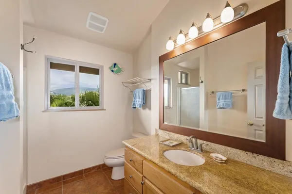a bathroom with a granite countertop sink toilet and mirror