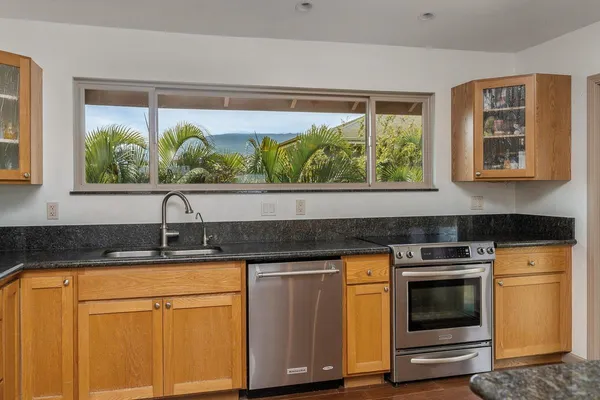 a kitchen with granite countertop white cabinets and a stove top oven