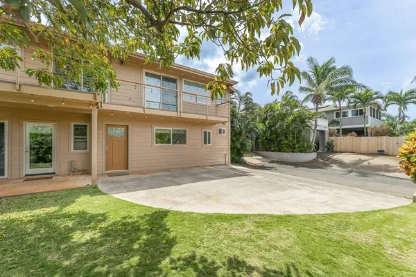 a view of a yard in front of a house with a large tree