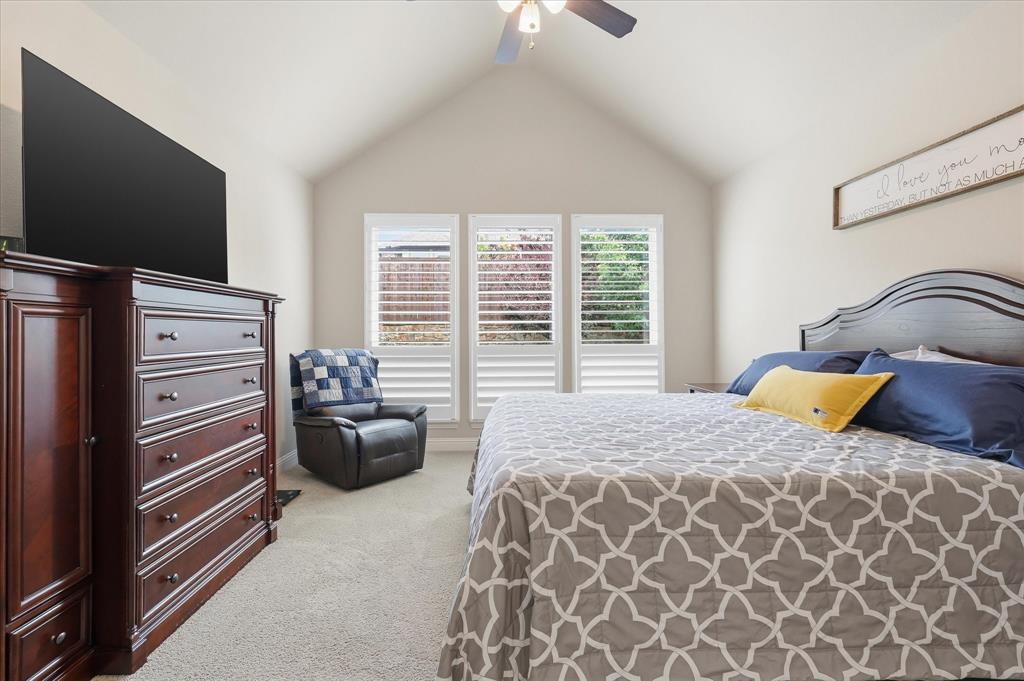 9708 Surveyor Road Oak Point, TX 75068 - Photo 18 of 34 Primary Vaulted ceiling with a ceiling fan, three windows with plantation shutters, carpet flooring, and ample wall space