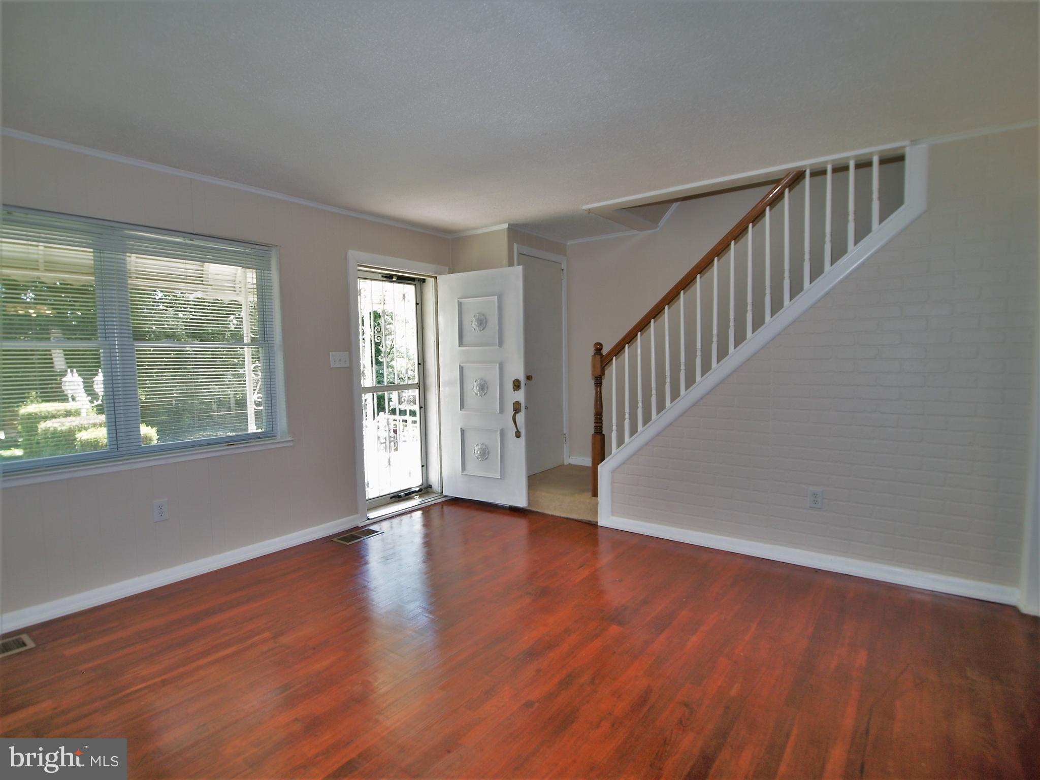 652 Charraway Road Baltimore, MD 21229 - Photo 4 of 22 a view of an empty room with wooden floor and a window