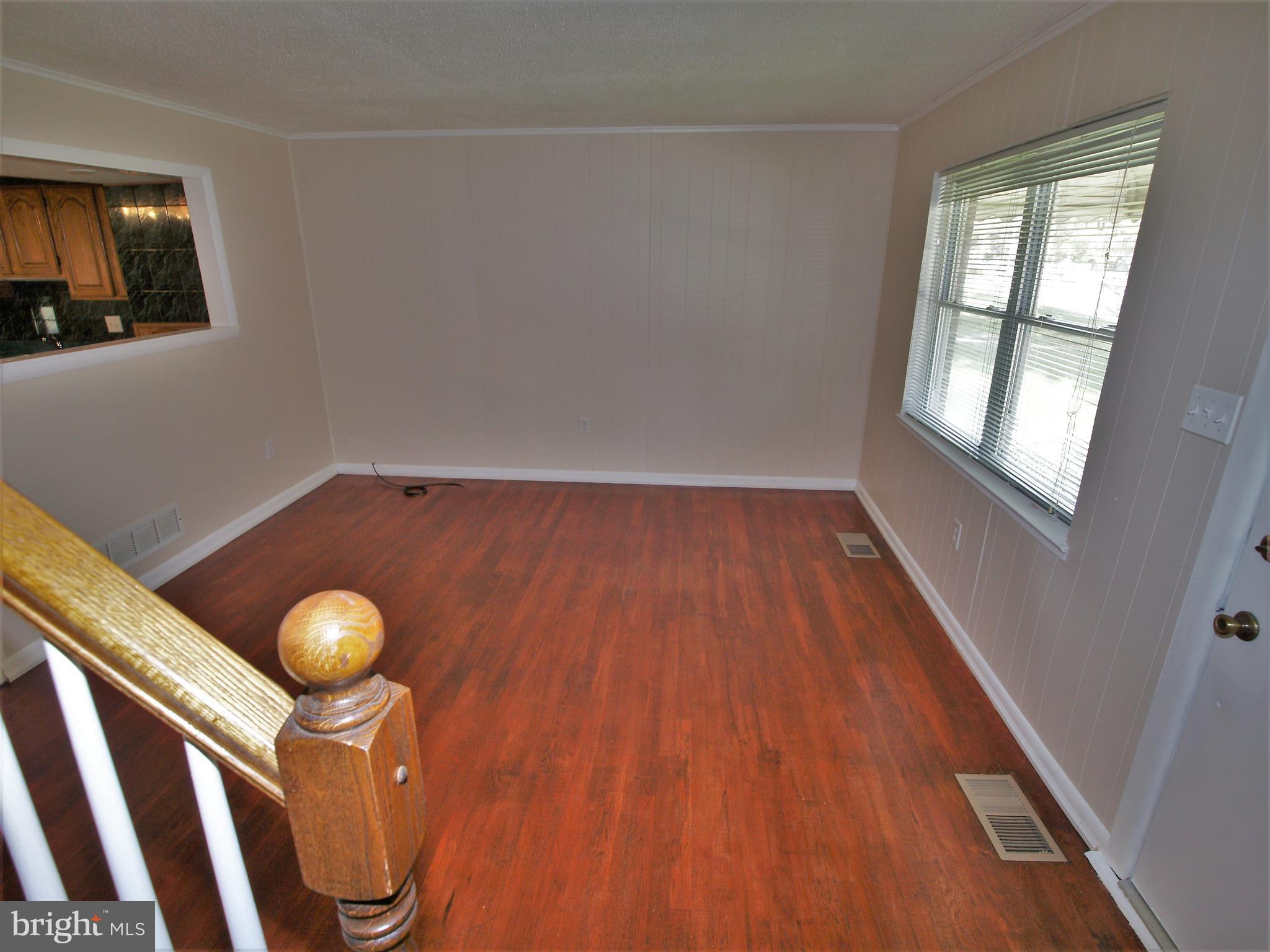 652 Charraway Road Baltimore, MD 21229 - Photo 5 of 22 a view of an empty room with wooden floor and windows